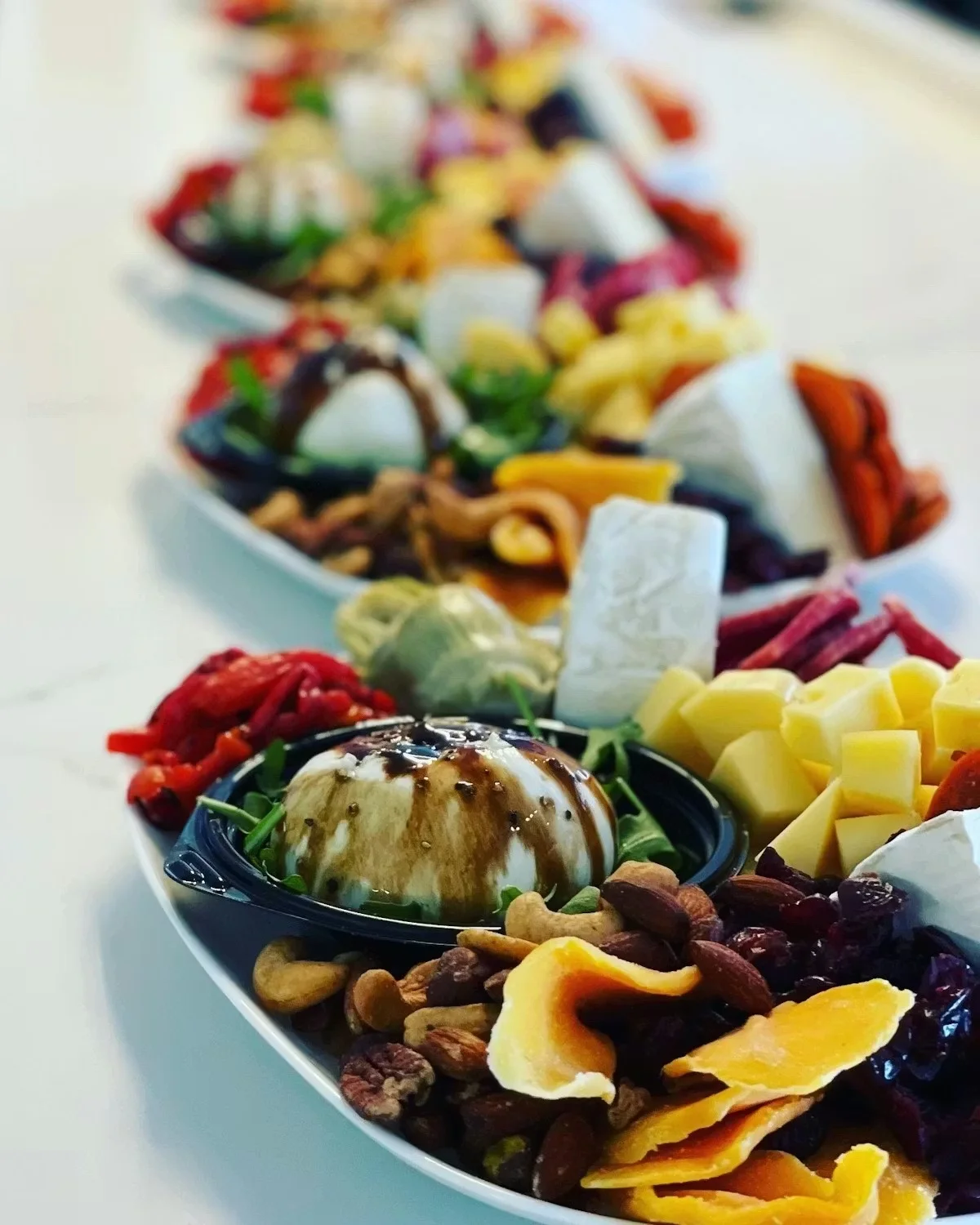 A beautifully arranged platter of assorted cheeses, nuts, and fruits.