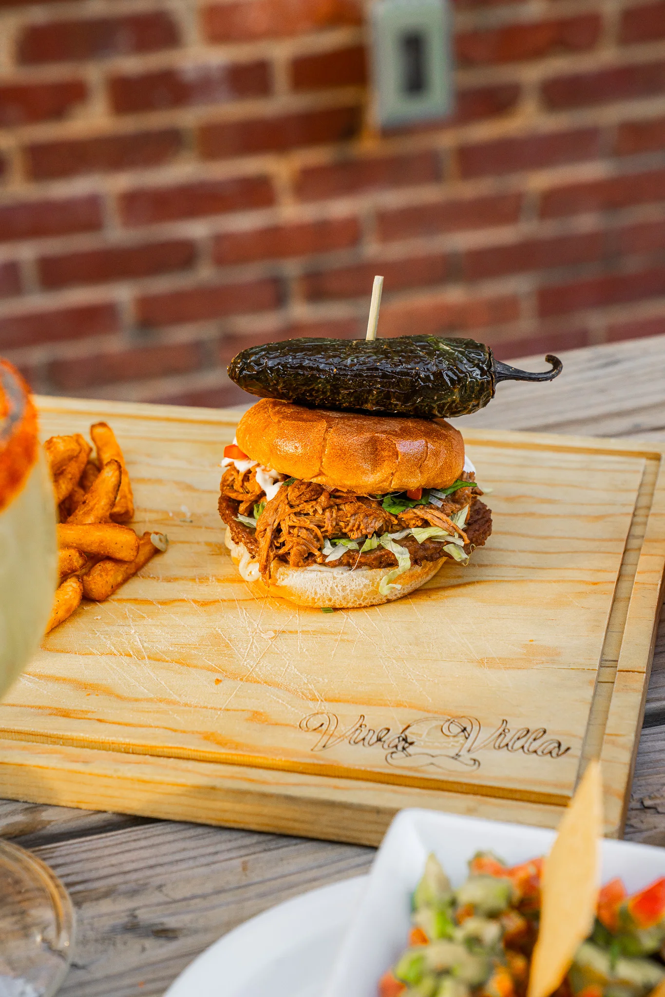 Pulled pork sandwich with jalapeño on a wooden board