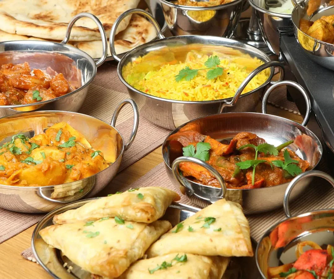Assorted Indian curries and naan bread served in traditional bowls