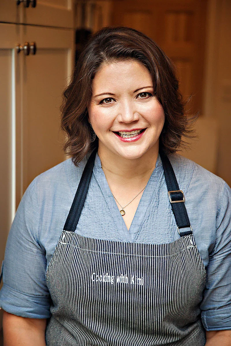 Chef smiling in a kitchen wearing an apron