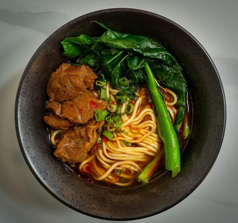Bowl of Chinese beef noodle soup with greens