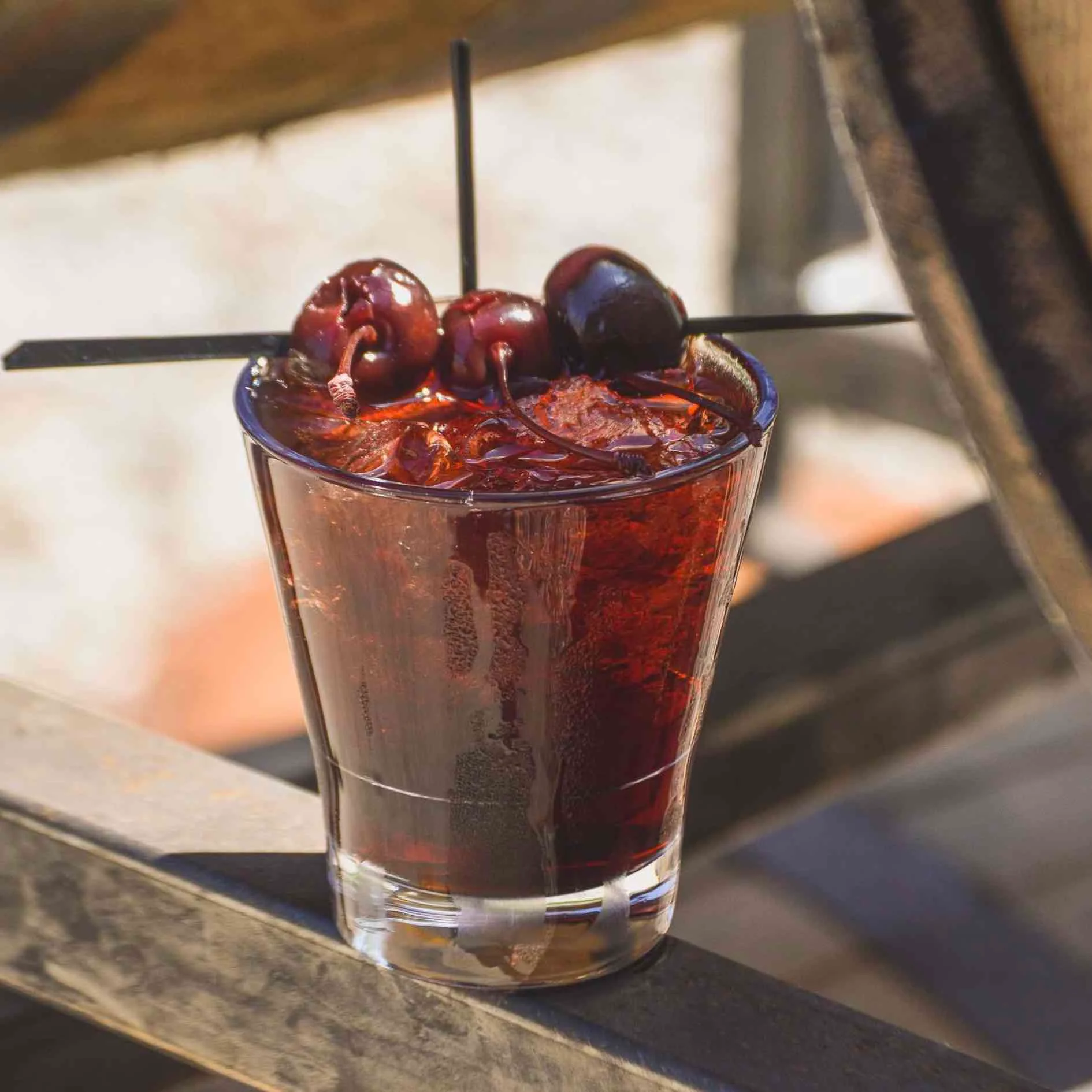 Manhattan cocktail sitting below some barrels in the shade