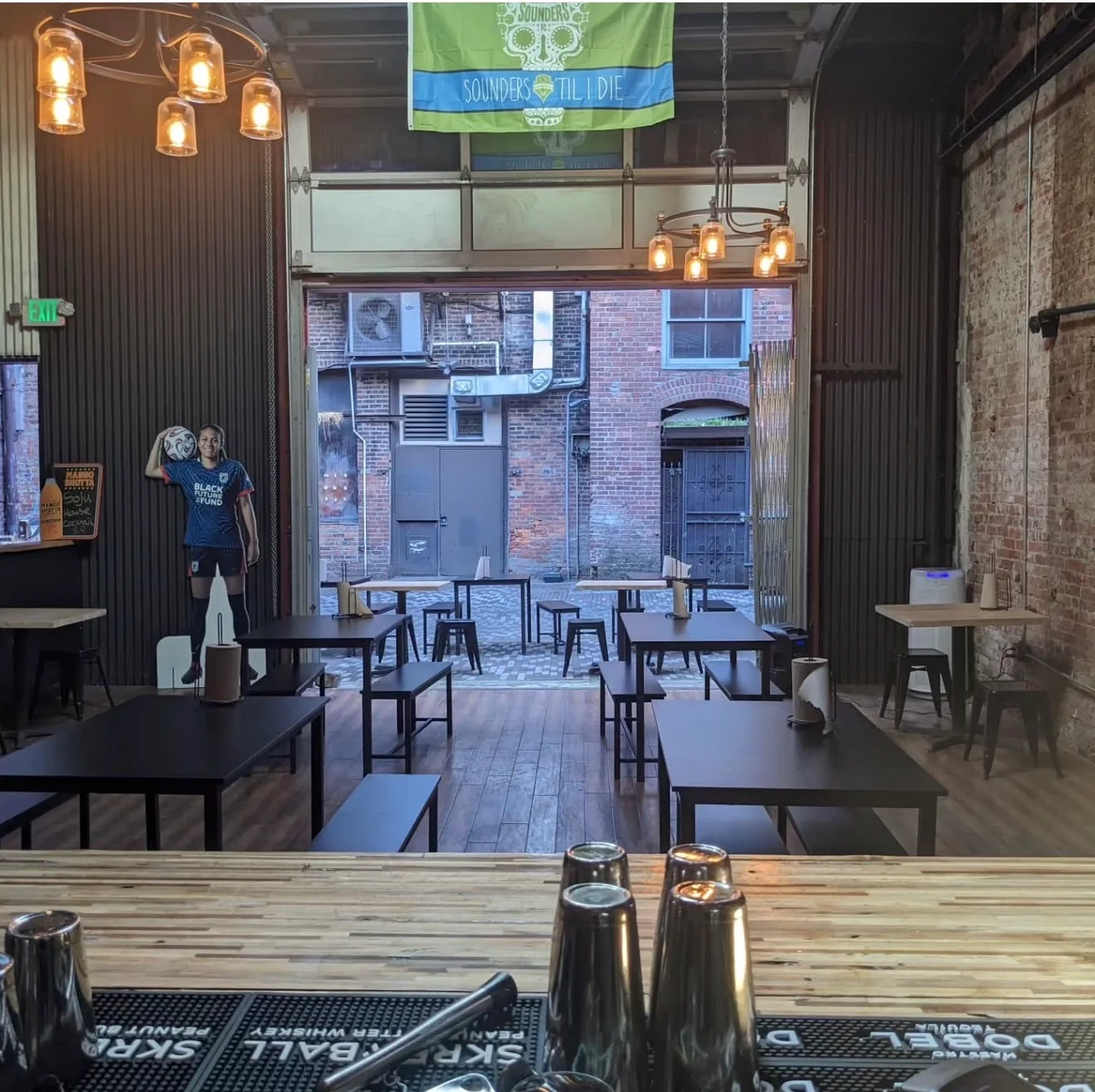 An indoor space with a bar and tables, showcasing a soccer-themed decoration and a flag on display.