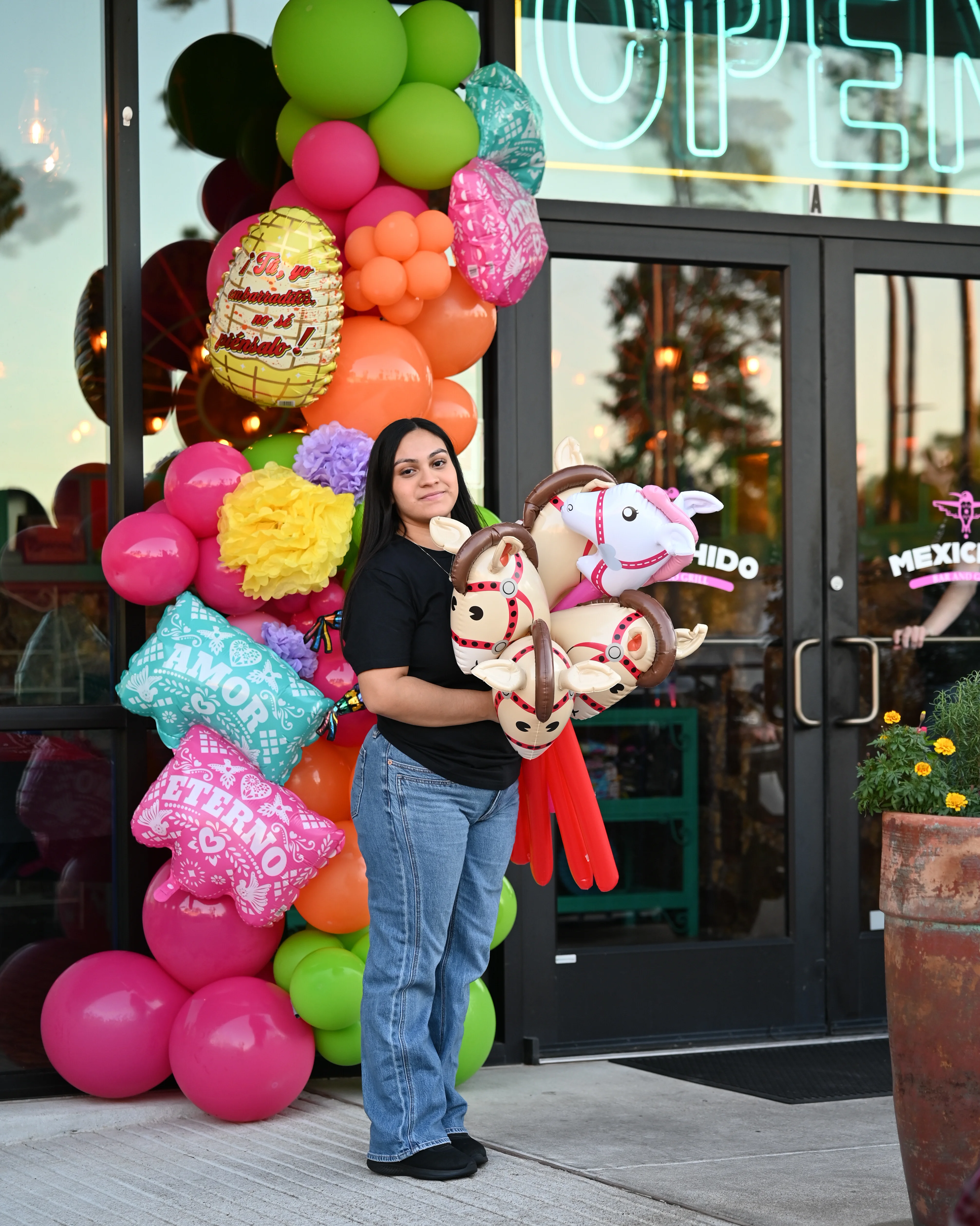 Colorful balloon display outside a restaurant with a smiling staff member