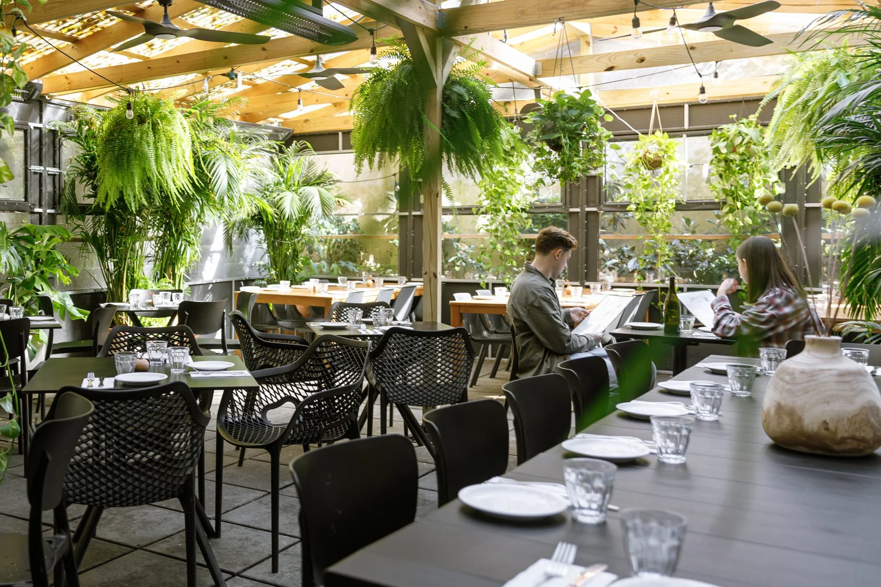 Covered outdoor dining room with plants at Chama Mama Chelsea