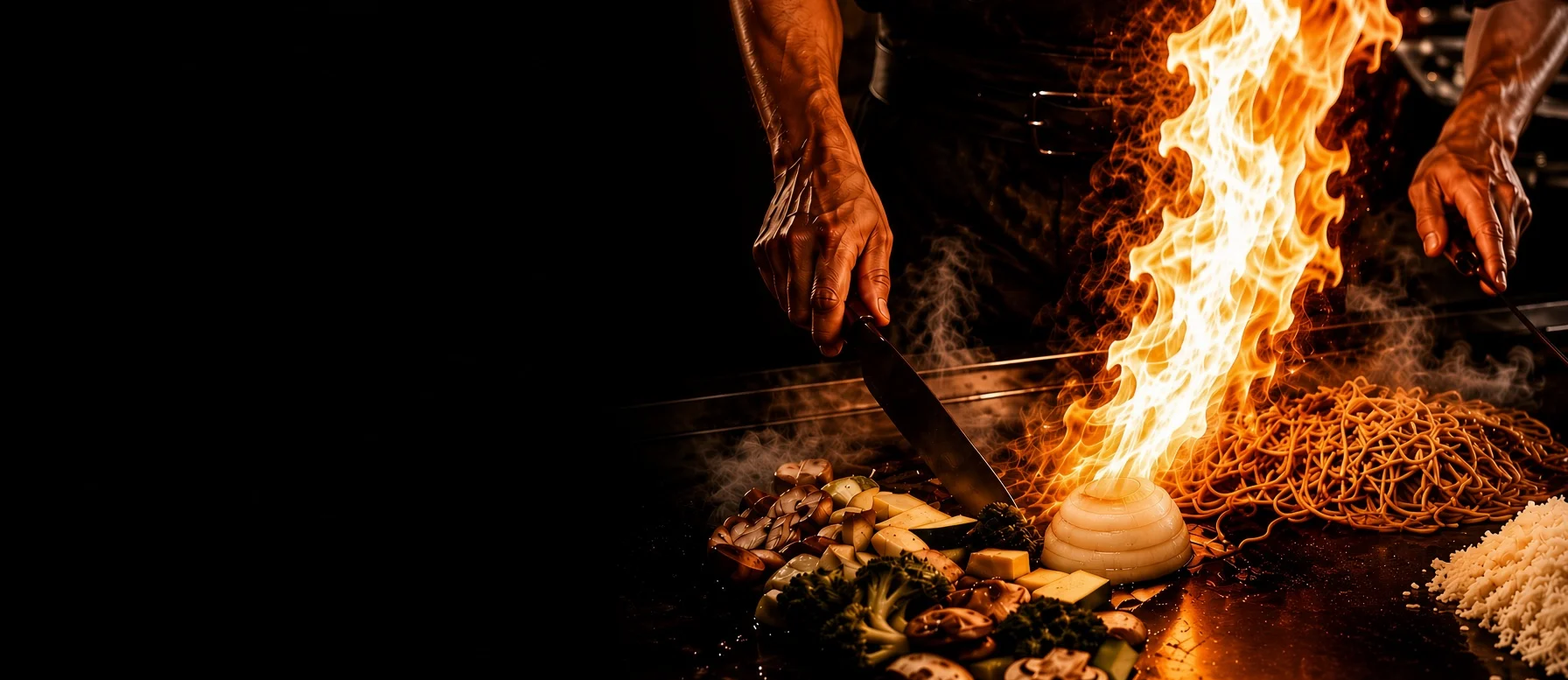 Teppanyaki chef creating a flame display with vegetables and noodles