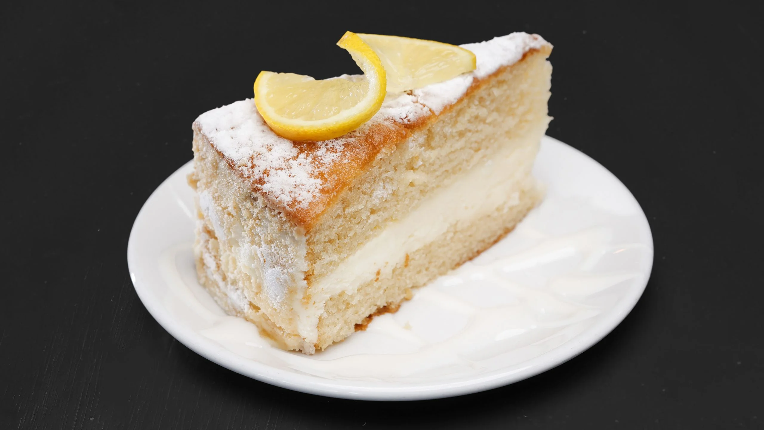 Lemon cake slice with creamy filling and powdered sugar