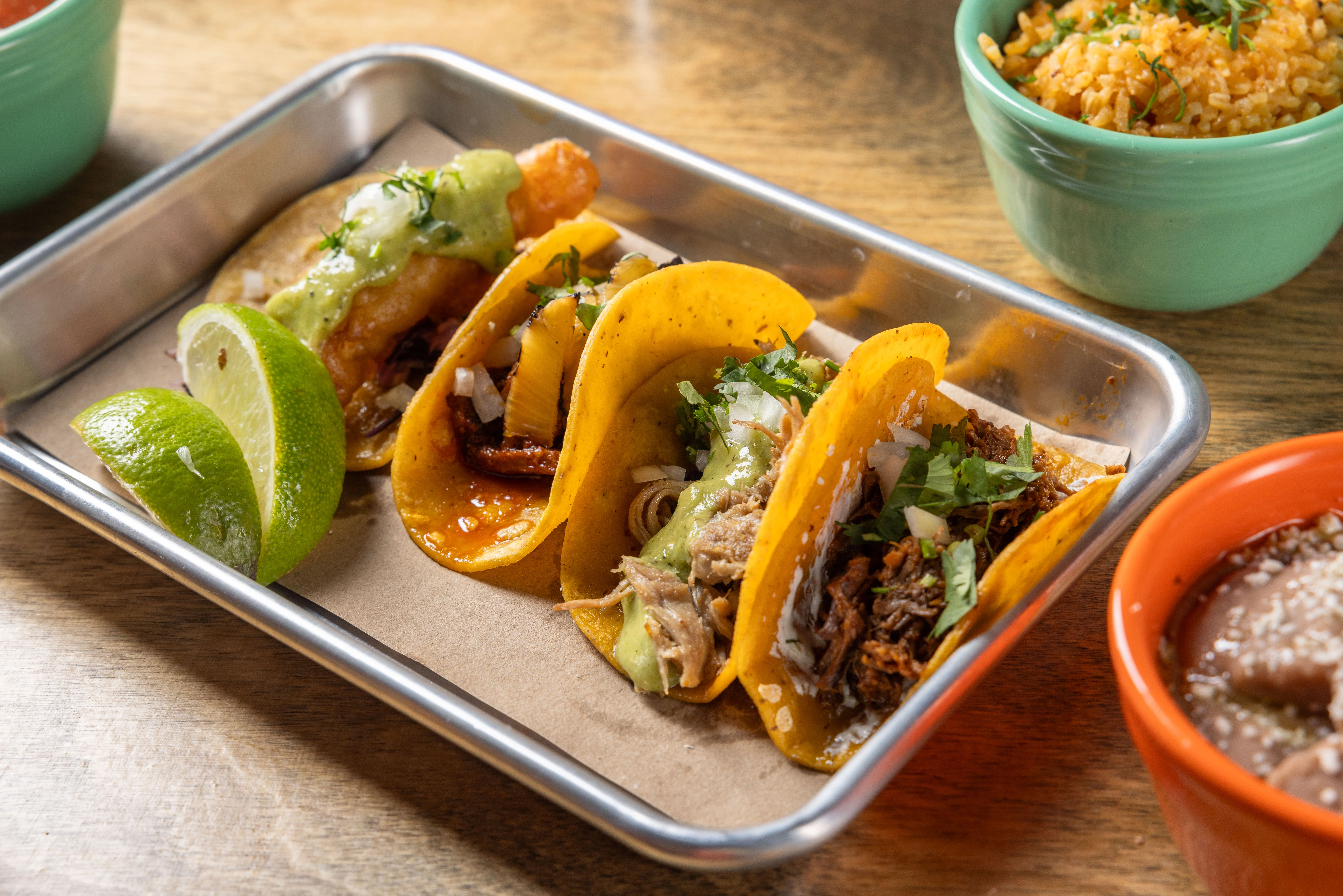 Assorted Mexican tacos with lime and rice on a wooden table