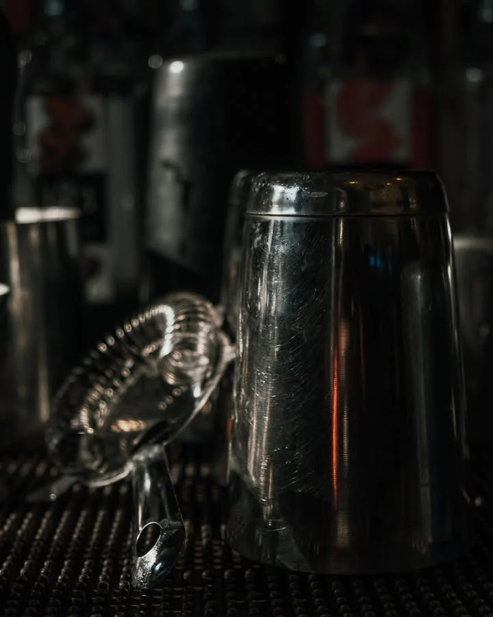 Bartender tools and cocktail shaker on a bar counter