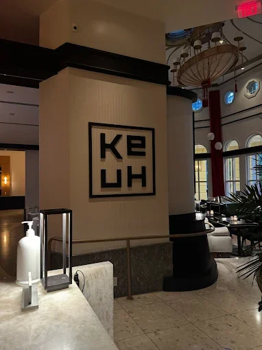 The entrance of Ke-uH Restaurant, Sunny Isles Beach location featuring high ceilings, arched windows, and a large decorative light fixture.