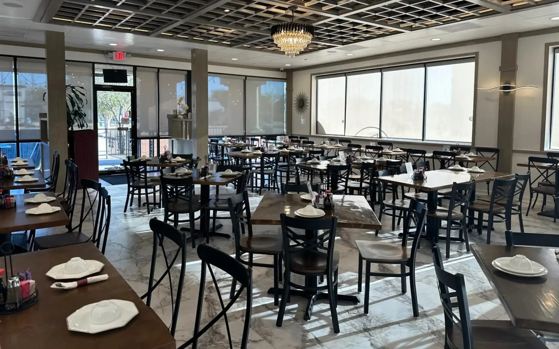 Spacious restaurant interior with tables set for dining and large windows.