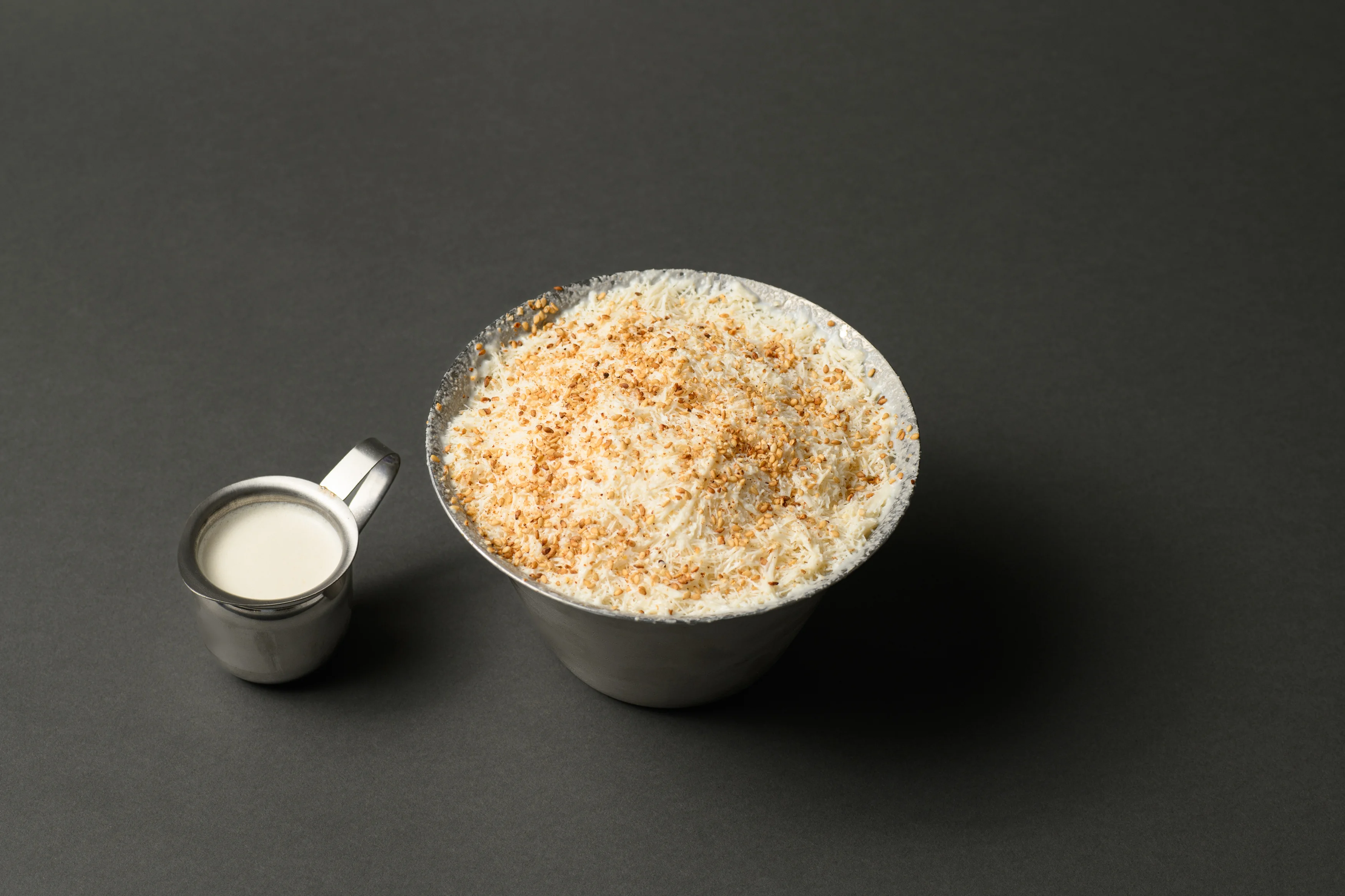 Bowl of Indian coconut burfi topped with toasted nuts