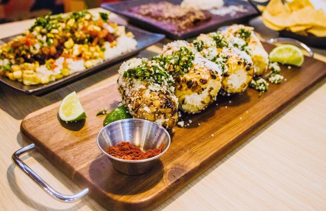 Grilled Mexican elote served on a wooden platter