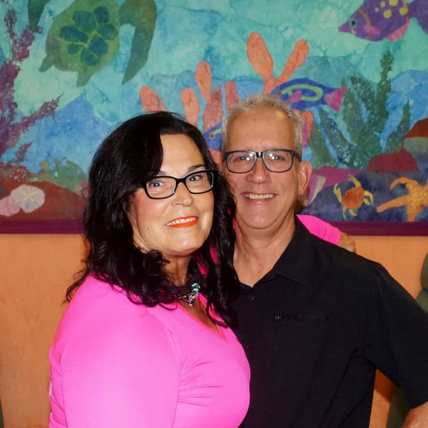 Couple posing in a vibrant restaurant with colorful mural backdrop
