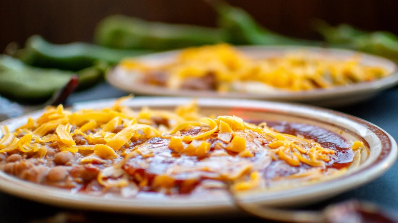 Plate of enchiladas topped with cheese and red sauce