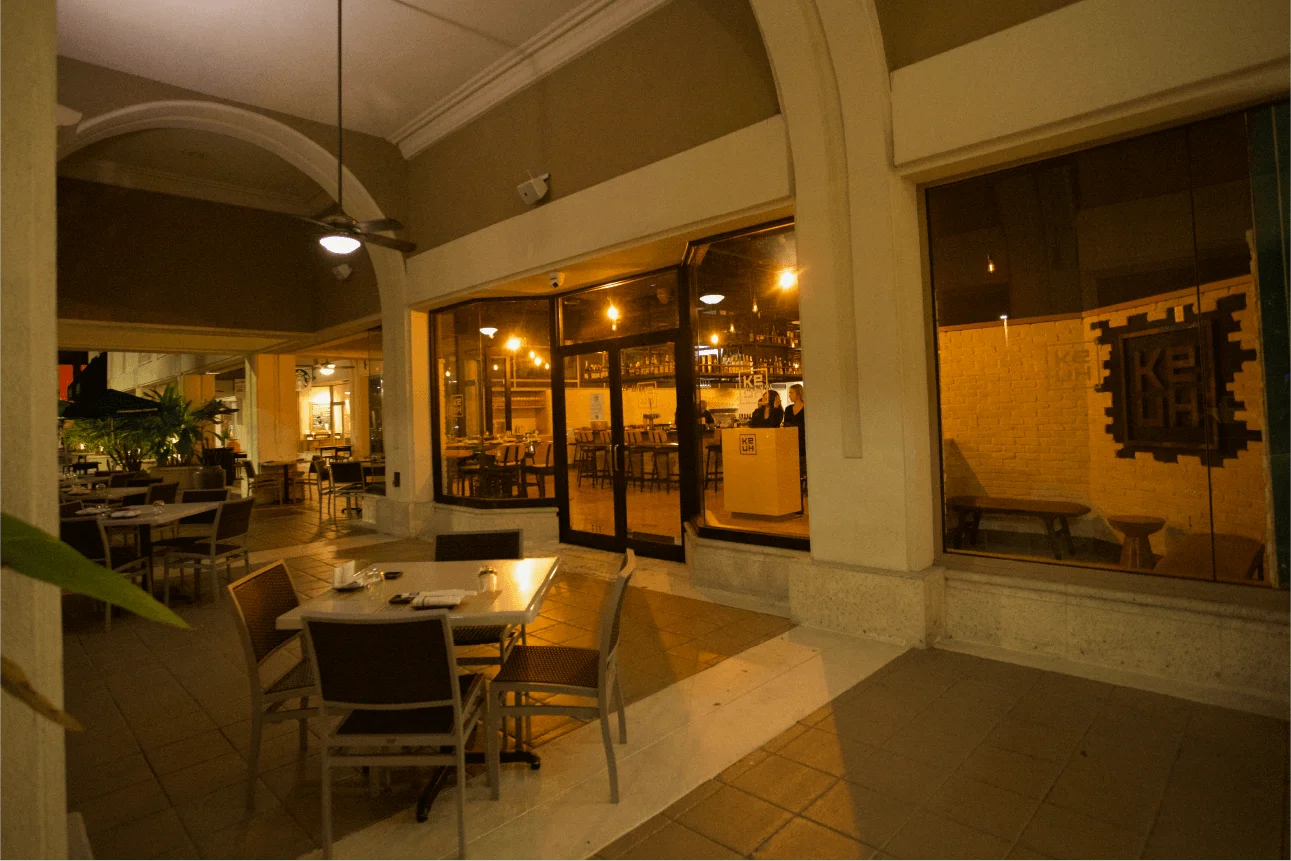 The illuminated storefront and covered outdoor patio of Ke-uH Boca Raton at night