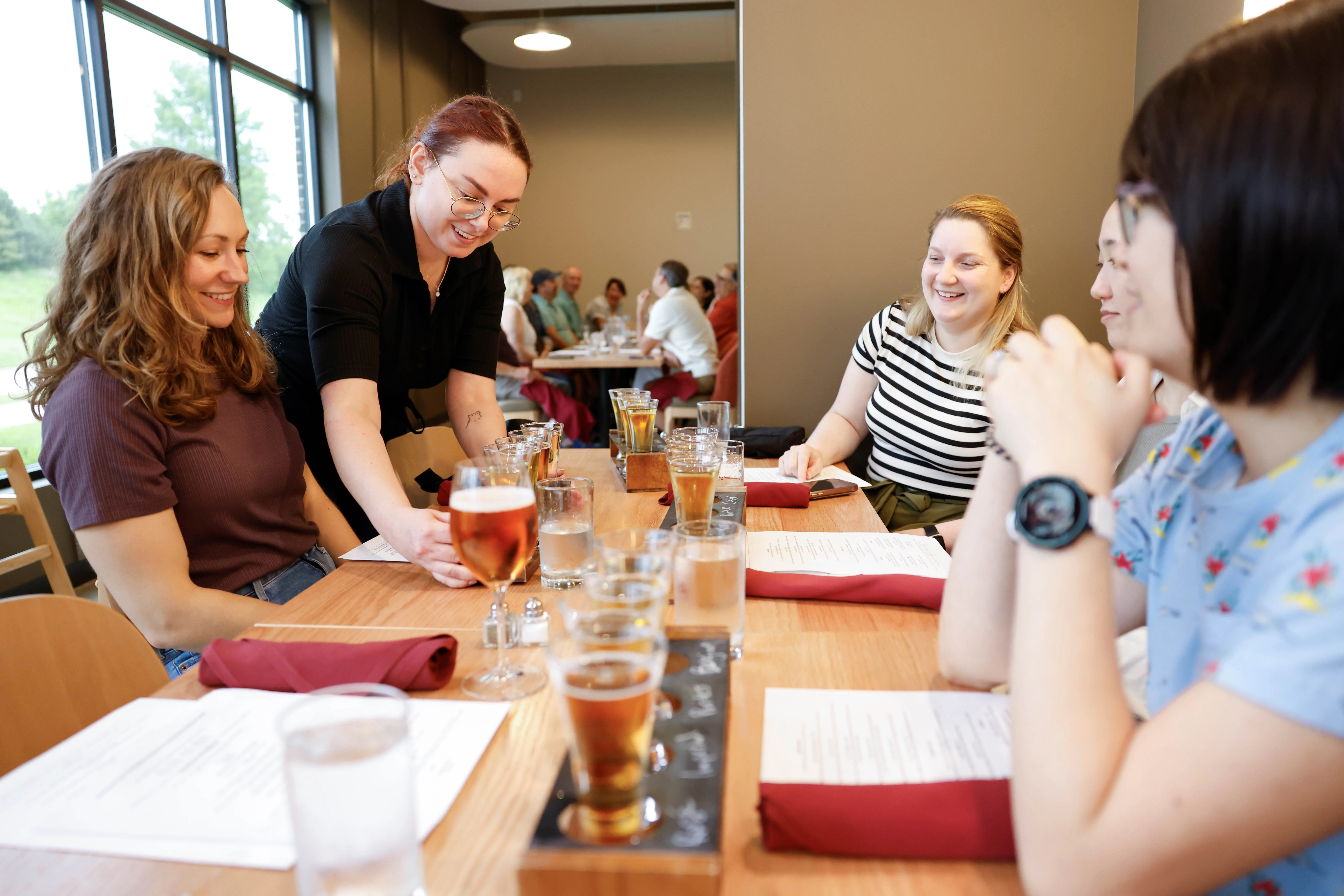 Friendly server serving drinks at a lively restaurant table
