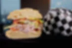 Delicious sandwich with fresh ingredients and a soccer ball in the background