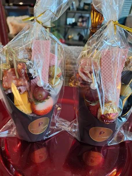 A colorful assortment of snacks served in trays, featuring cheese, fruits, and carrots.
