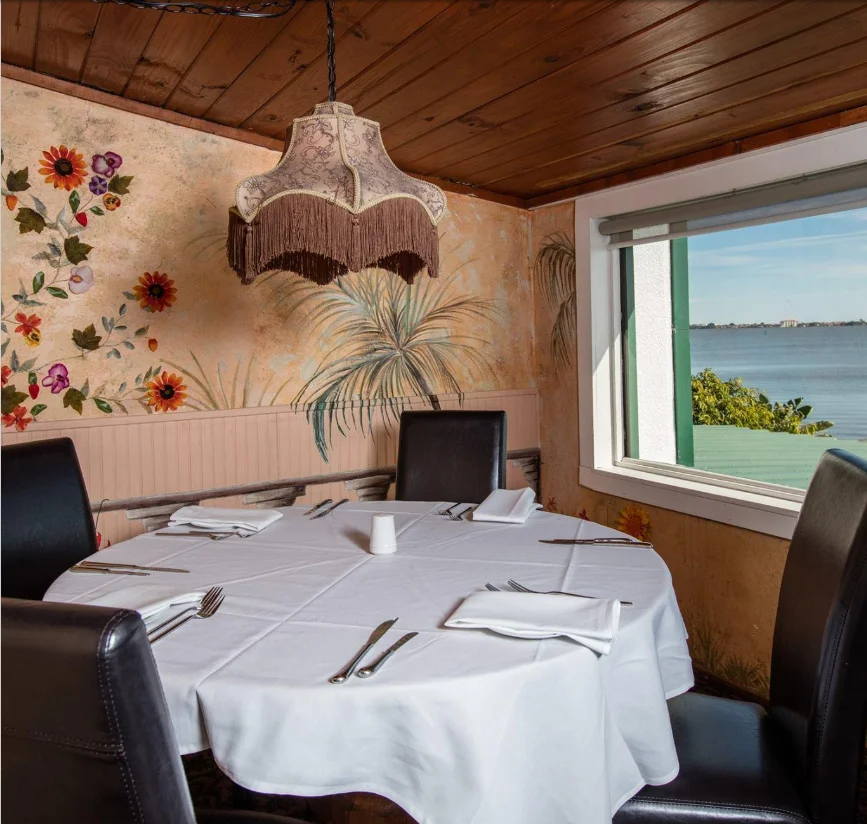 Cozy restaurant dining area with floral mural and water view