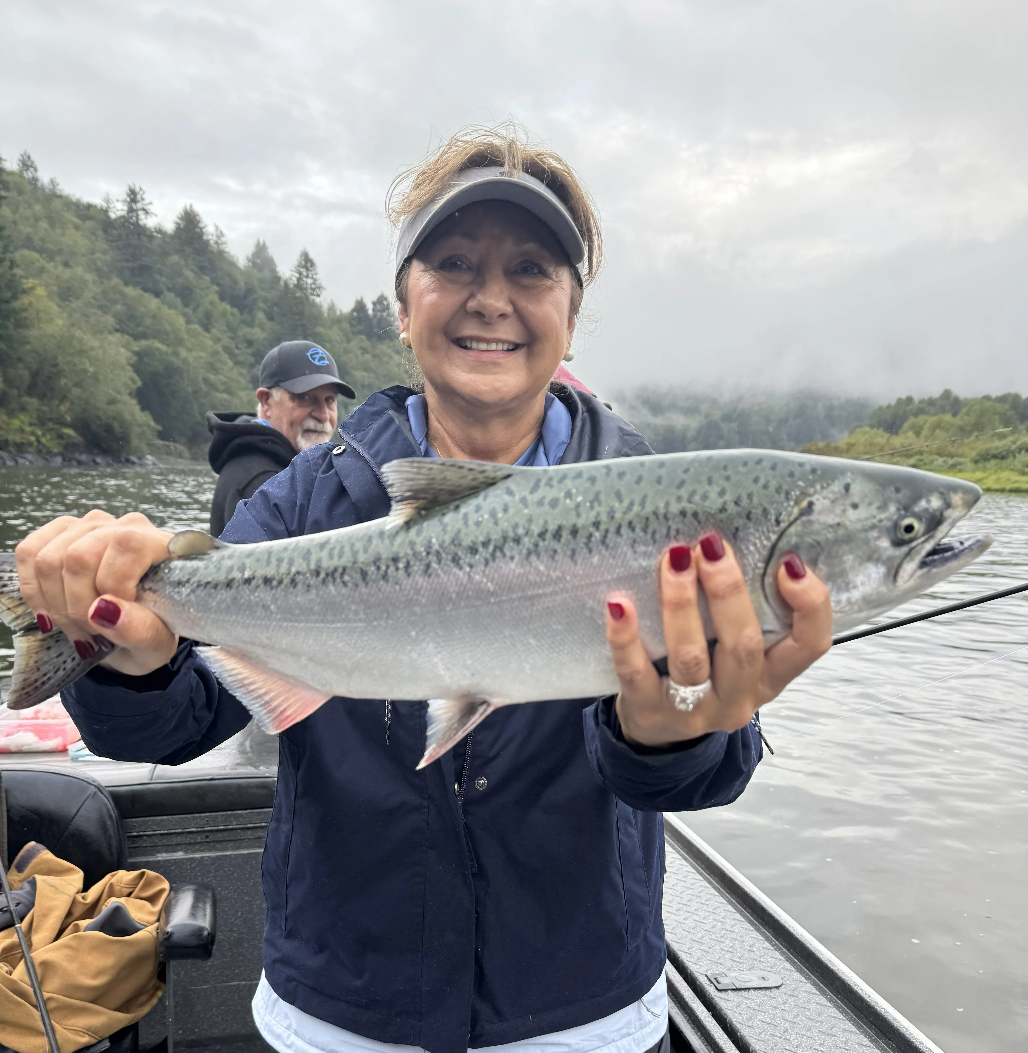 Angler proudly holding a large steelhead trout in a boat