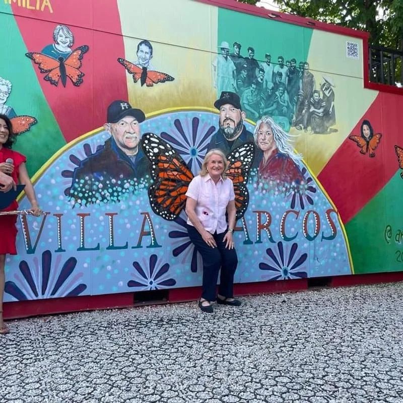 A smiling lady in front of the Villa Arcos mural
