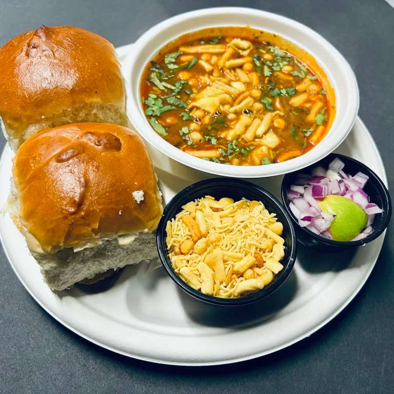 A food truck offering a variety of Indian dishes, showcasing small bread rolls filled with a spiced potato mixture on a tray.