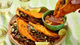 Delicious Mexican birria tacos with consommé and lime