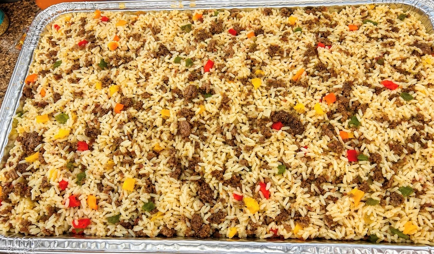 A large tray of rice mixed with ground beef and colorful bell pepper pieces, ready to serve.