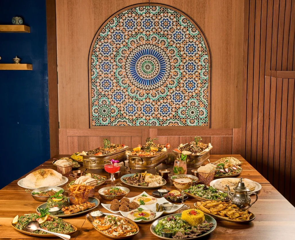Mediterranean restaurant meal featuring shawarma, rice, fresh vegetables, and house-made sauces.
