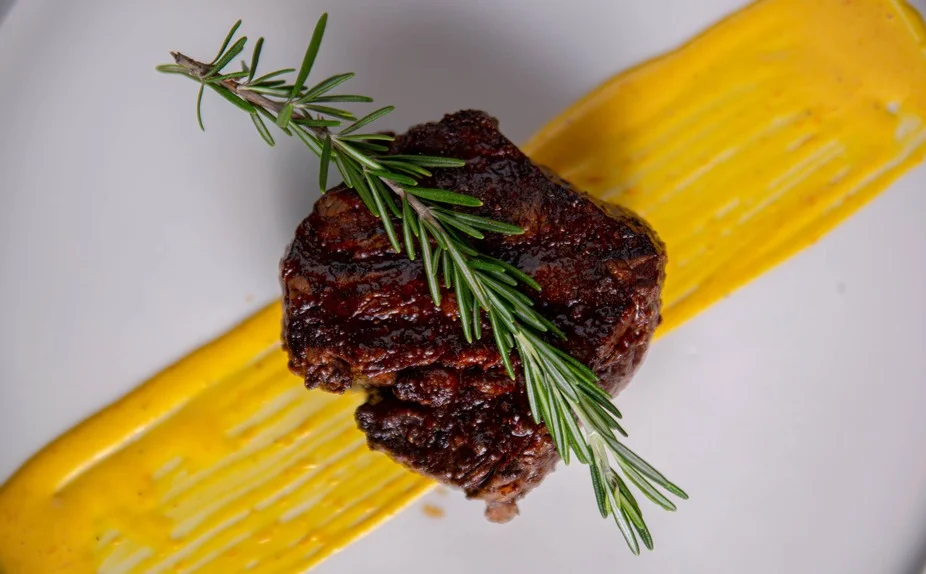 Grilled steak with mustard sauce and rosemary garnish