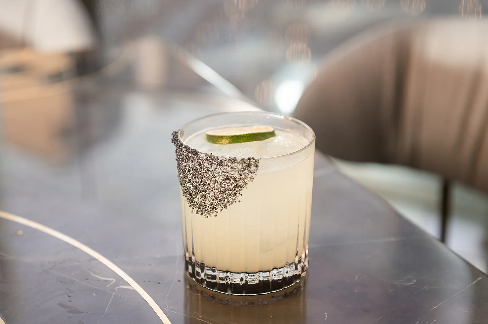 Craft cocktail with lime garnish and black salt rim