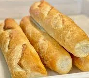 Freshly baked French baguettes on a wooden tray