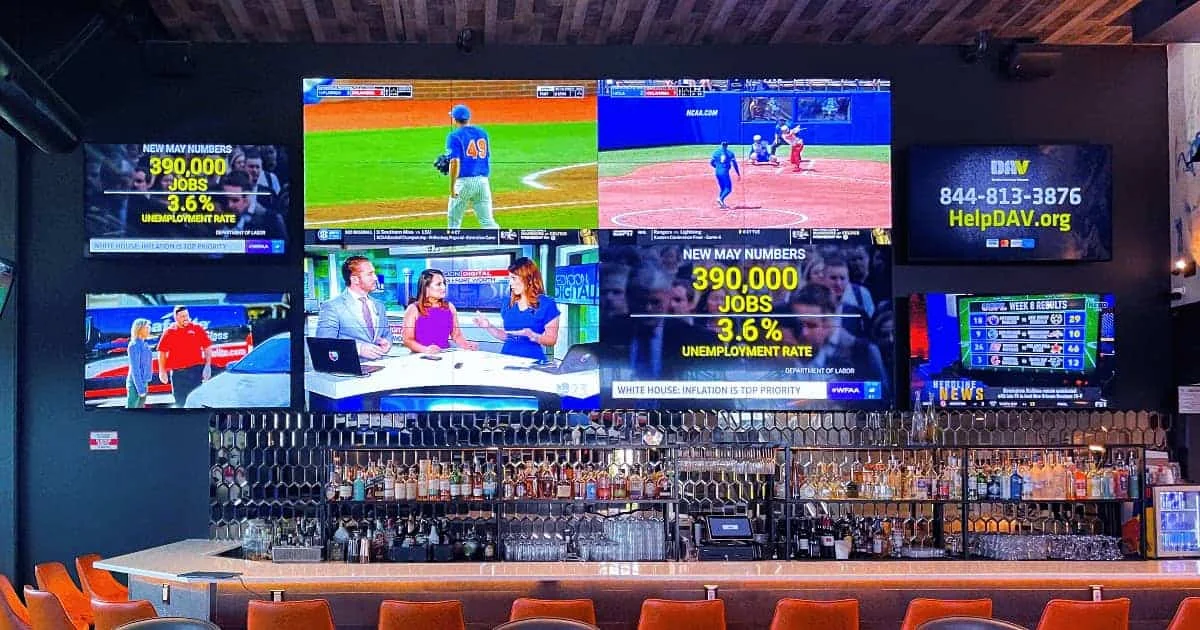 Sports bar interior with multiple screens showing games and news