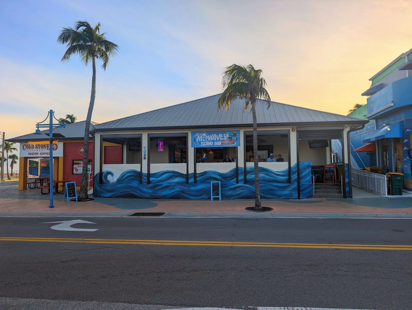 Colorful beachfront restaurant with palm trees and ocean mural