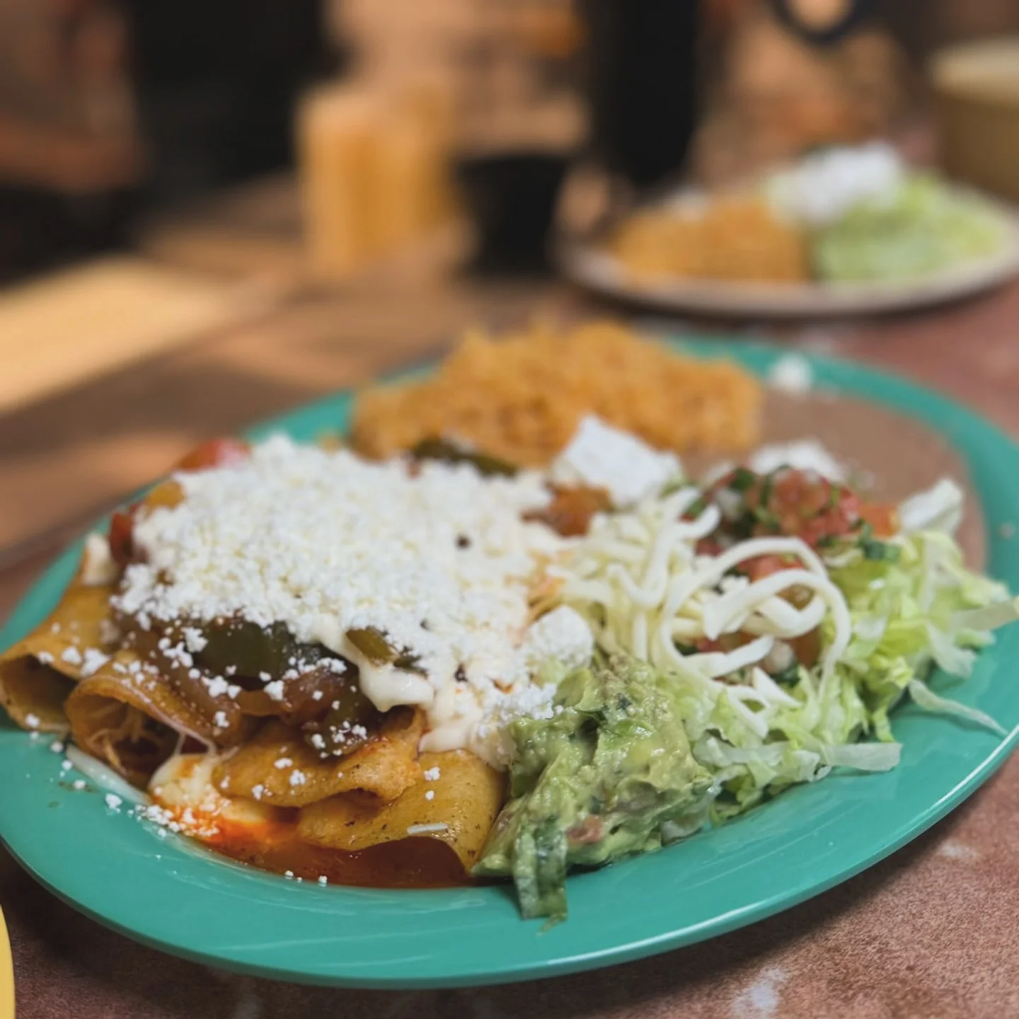 Plate of enchiladas topped with cheese and guacamole