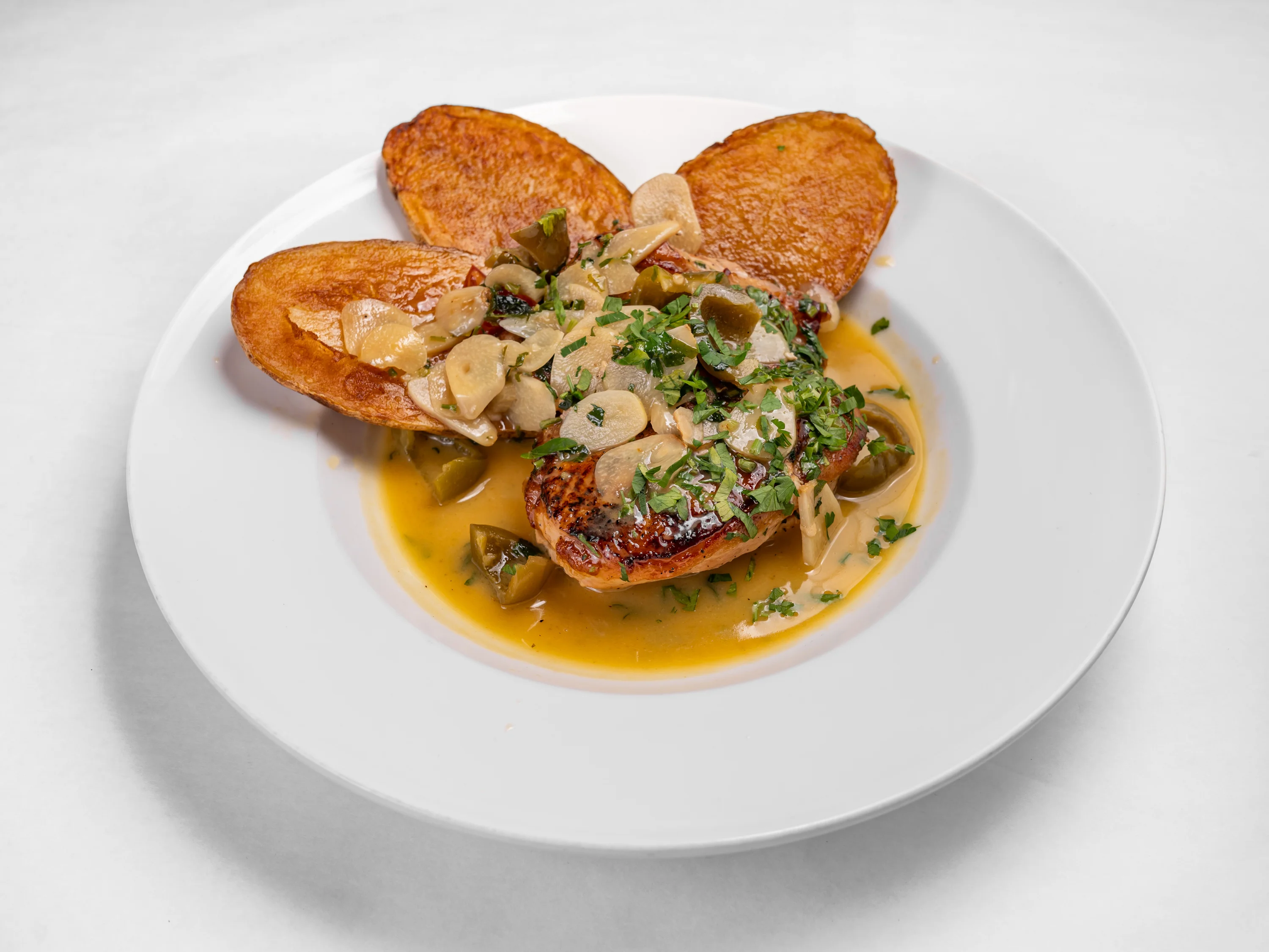 chicken scarpariello, with hot cherry peppers in white wine, over roasted potatoes.