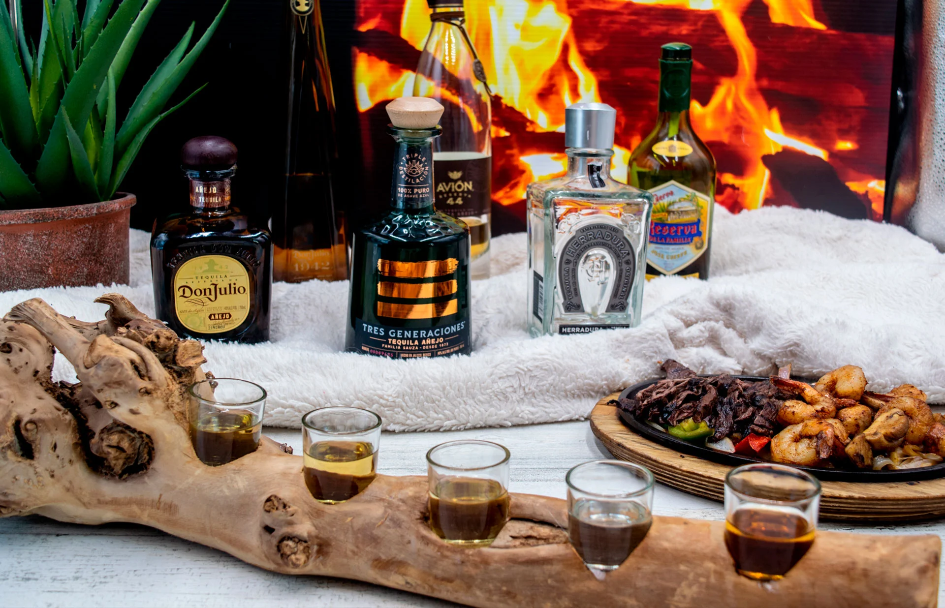 Table with different tequila bottles, with a shot glasses and fajitas