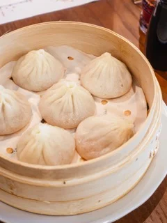 Delicious xiaolongbao dumplings served in a bamboo steamer.
