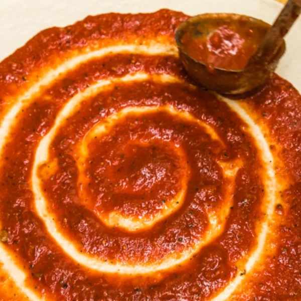 Spiral of marinara sauce on pizza dough