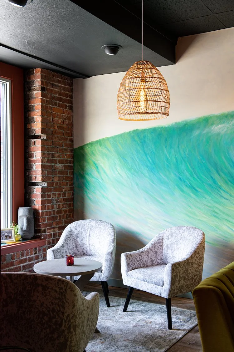 Stylish restaurant lounge with colorful mural, brick wall, and pendant lighting