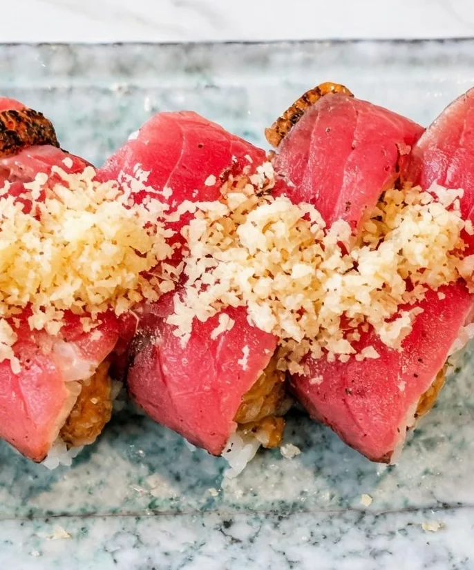 Japanese sushi rolls topped with seared tuna and crispy garlic