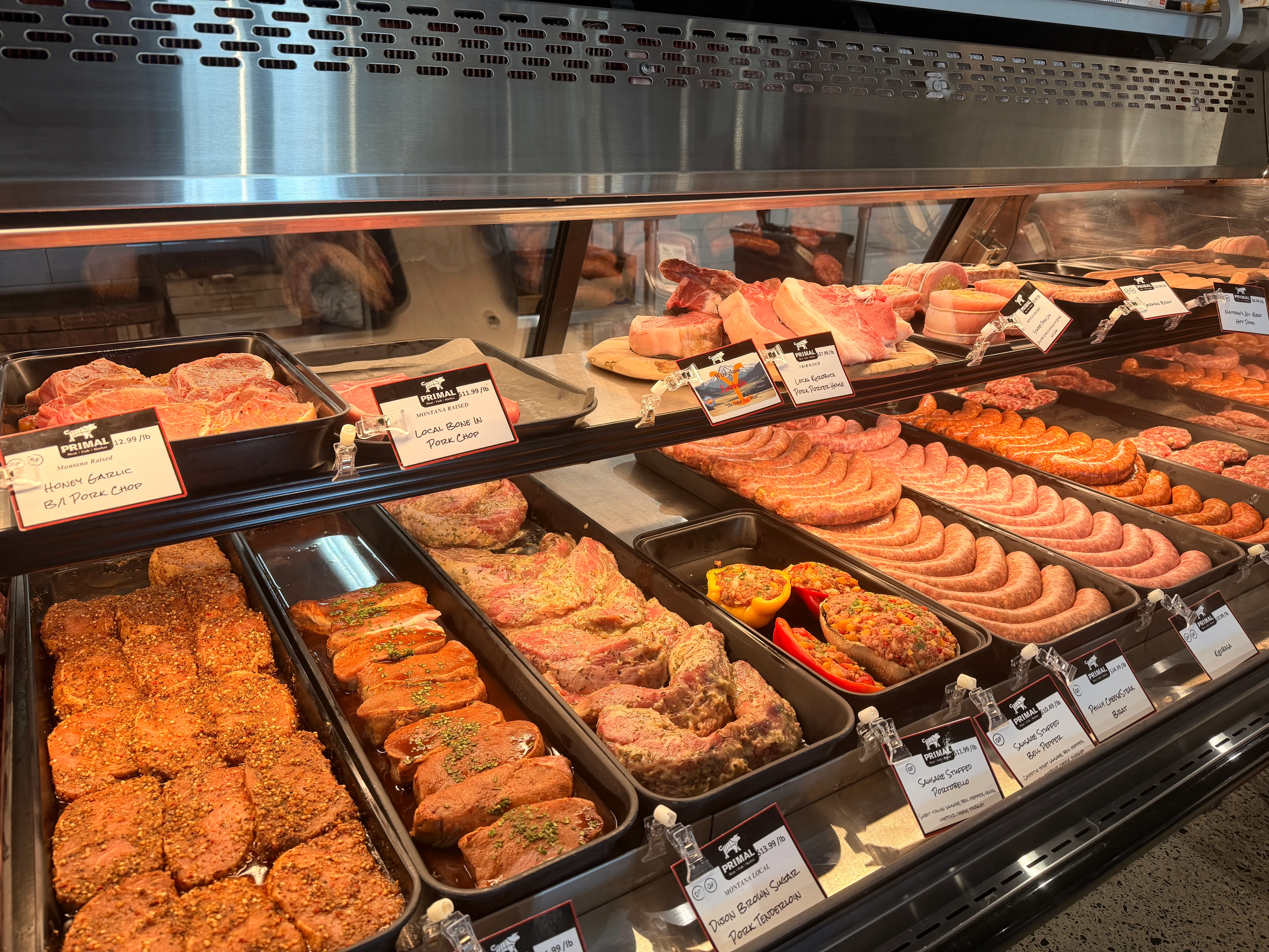 Butcher counter displaying marinated steaks and sausages