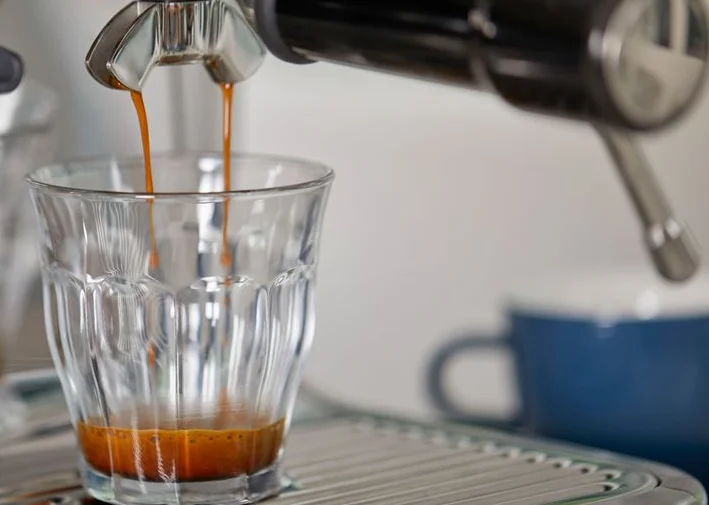 Espresso pouring into a glass cup from a coffee machine