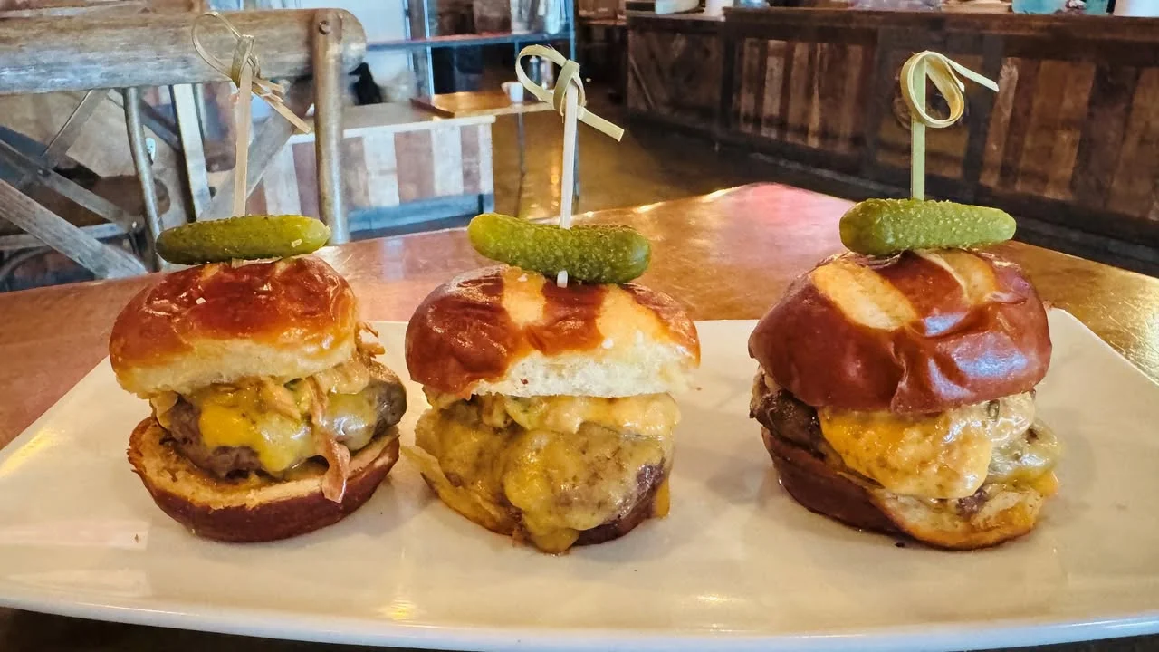 Umami sliders with American cheese, mushrooms, crispy garlic, chili sauce, and pretzel buns