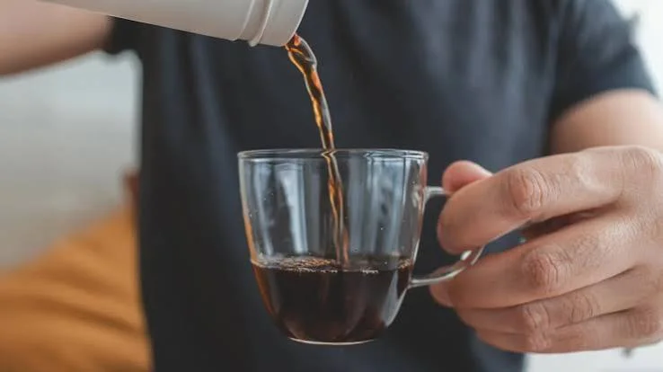 Pouring coffee into a clear glass cup