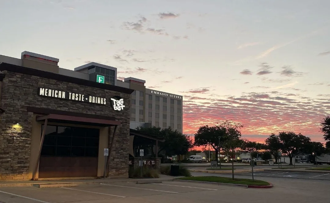Restaurant exterior at sunset with illuminated Taqueria bar signage