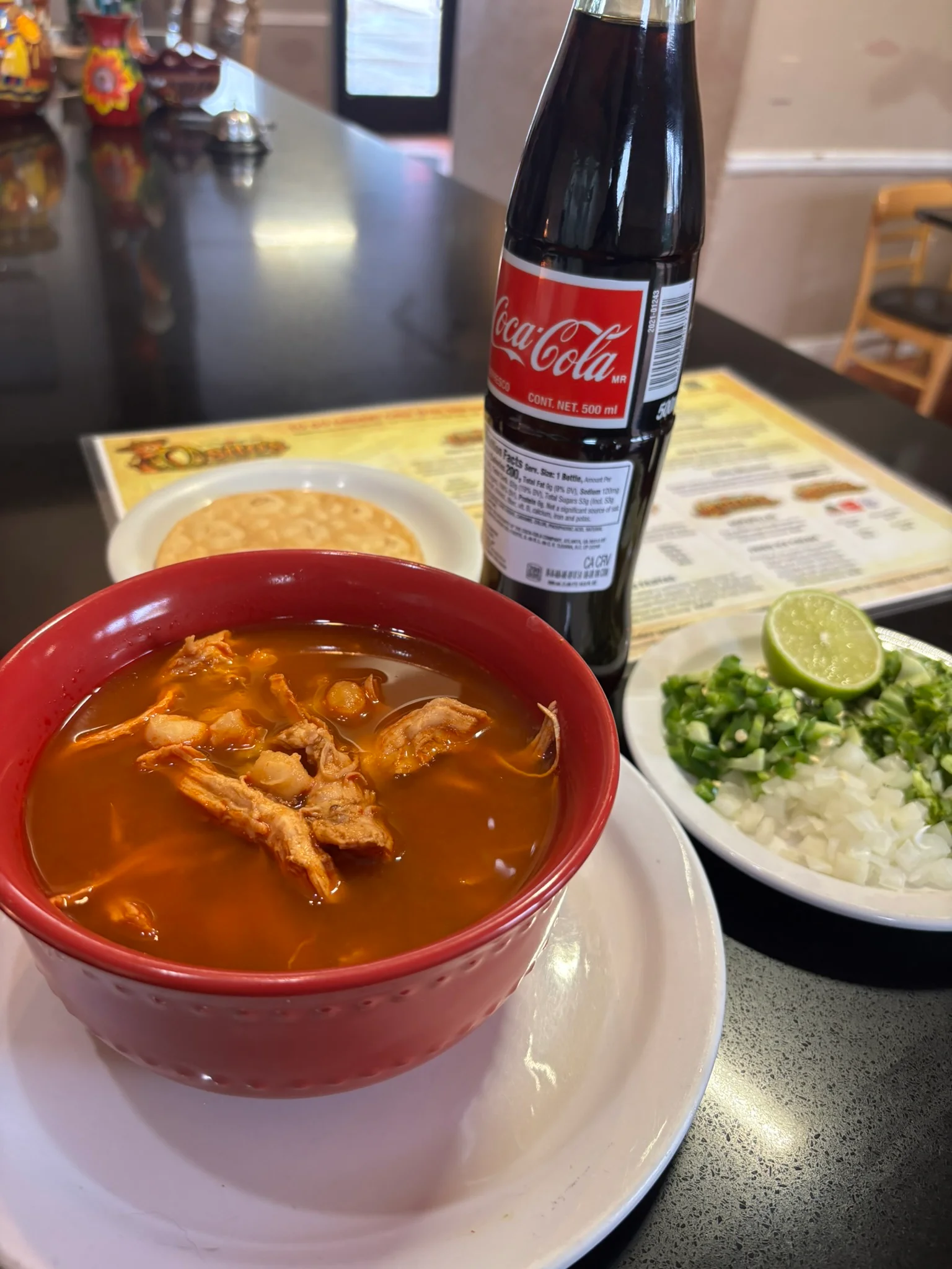 Authentic Mexican pozole rojo served with lime and toppings