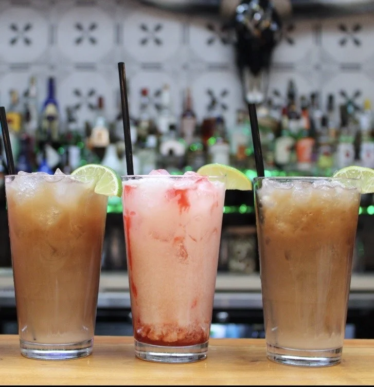 Colorful cocktails with lime garnishes at a vibrant bar