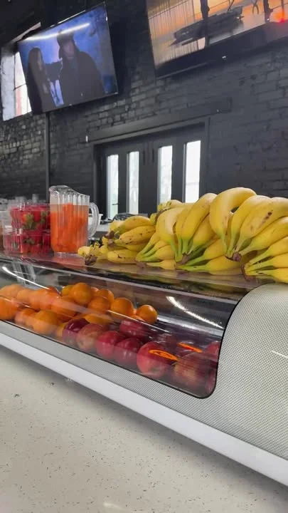 Fresh fruit display with bananas, oranges, and strawberries in a modern café